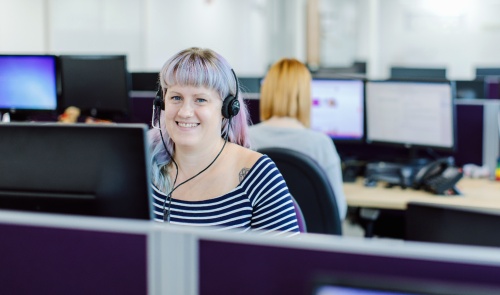 Female advisor sat at her computer, smiling.
