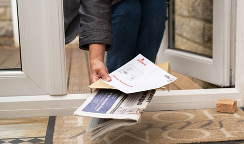 woman picking up bills from doorstep