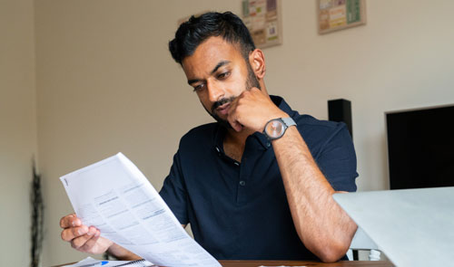 young man looking at bills at table