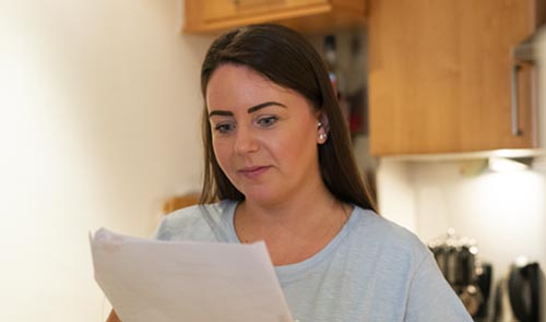 Young woman reading a document in a kitchen