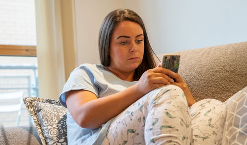 young woman in pyjamas looking at her phone