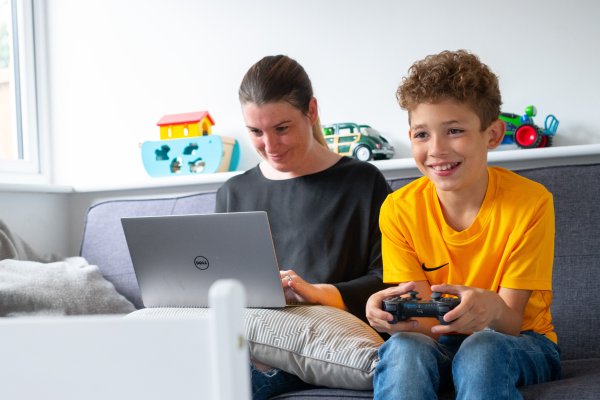 Mum on laptop while son plays video games