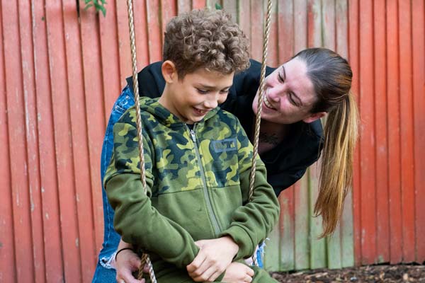 Mum pushing son on swings