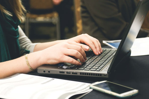 A close up of hands typing on a laptop computer