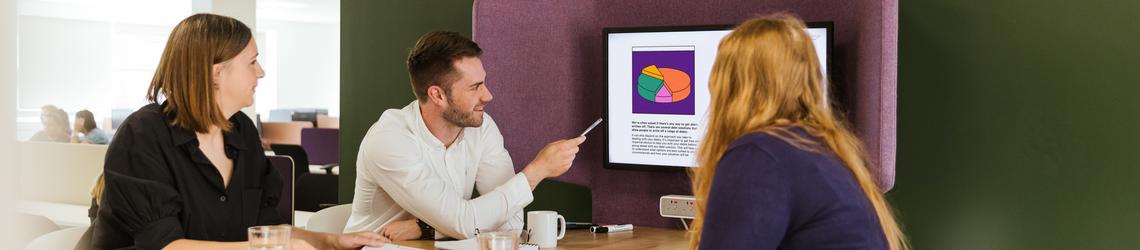 man and two women smiling in a meeting at work