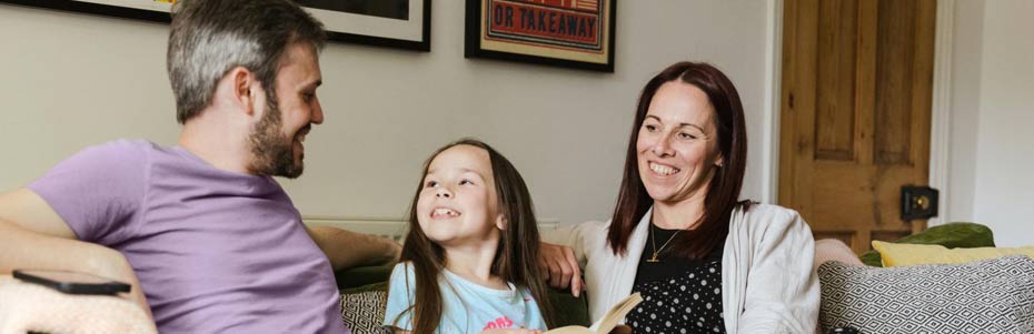 family of three sitting on the couch together