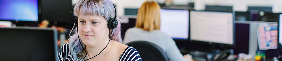 Female StepChange advisor in support centre with headset on