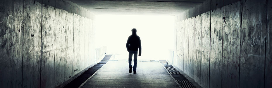 A man walking towards light at teh end of a large tunnel