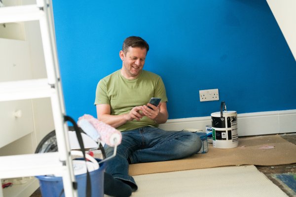 man sat on the floor next to paint tin