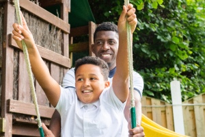 dad pushing son on swing