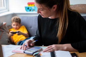 mum sorting paper work while son plays video games