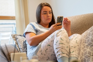 woman sat in pjs on her phone