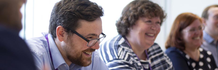 man and two women smiling in a meeting at work
