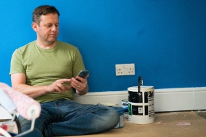 man sat on the floor next to paint tin